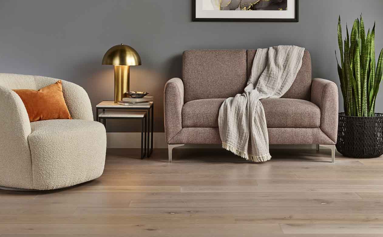 mid-tone Hardwood Flooring in modern Living Room with boucle chair and gold table lamp